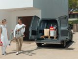 A couple with a Nissan Townstar filled with supplies in the background